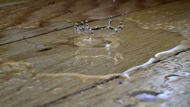 Water droplet splashing on a wet wood plank floor